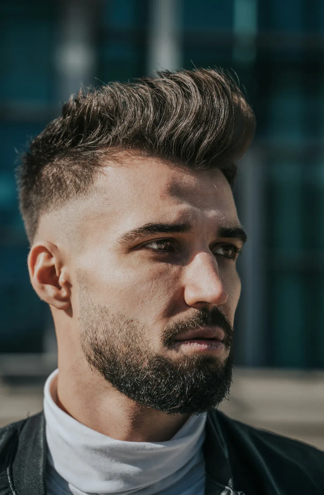 Homem de barba com o topo texturizado penteado para cima e a lateral curta em degradê